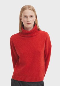 Roter Pullover mit geripptem Rollkragen, lockerer Passform und weicher Textur. Mit überschnittenen Schultern und geripptem Saum für zusätzliche Details.