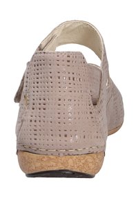 Beige sandaal met een gestructureerd, geperforeerd leren bovenwerk, open achterkant ontwerp, kurken zool en minimale stikdetails.