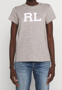 Grå kortärmad t-shirt i bomull med rundad halsringning och en stor vit "RL"-logotyp på framsidan. Matchas med blå denimjeans.