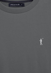 T-shirt grigio scuro con scollo rotondo, etichetta "POLO CLUB" e piccolo golfista bianco ricamato che tiene una mazza sul petto.