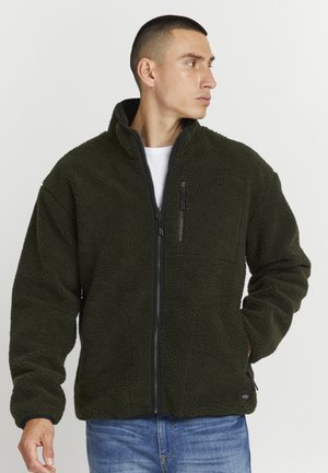 Fleece jacket in dark green, featuring a high collar, full zipper, chest pocket, and textured surface. Roomy fit with long sleeves.