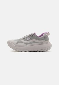 Zapatilla gris con detalles en púrpura, con un cuello acolchado, paneles texturizados y una suela gruesa y con dibujo para mayor tracción.