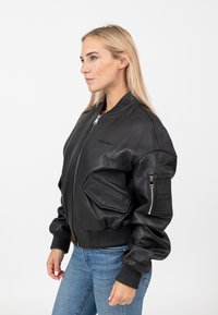 Zwarte leren bomberjack met geribbelde kraag en manchetten, voorzien van twee voorzakken en een ritszak op de arm, met een soepele textuur en een aansluitend design.