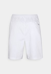 Shorts blancs à taille élastique avec une poche arrière et un petit détail noir et blanc sur le bord de la poche.