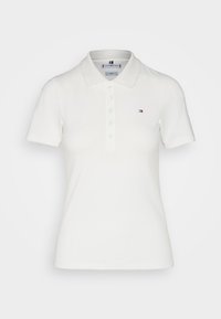Polo bianco in cotone, con colletto classico, maniche corte, cinque bottoni e un piccolo logo sul lato sinistro del petto.