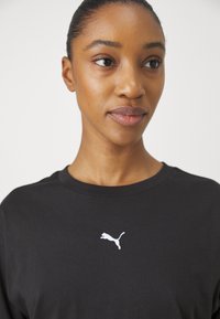 Black cotton t-shirt featuring a white Puma logo on the chest; round neckline and short sleeves, smooth texture, and casual fit.