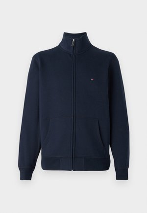 Tumedas sinises lahtise tõmblukuga sweatshirt, mis on valmistatud puuvillasegusest kangast. Omab seisvat kraed, kahte esist taskut ja väikest tikandiga logo rinnal.