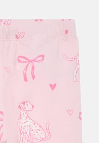 Vaaleanpunaiset legginsit, jotka on valmistettu pehmeästä kankaasta ja joissa on täpläisten koirien, nauhojen ja sydänten kuvio. Elastinen vyötärönauha mukautuu mukavasti.