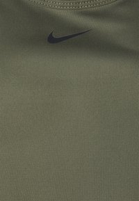 Olive green fitted athletic tank top with a smooth texture, featuring a black Nike logo on the upper left side. Seamless neck design.