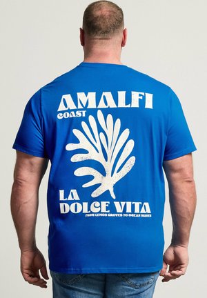 Mann trägt blaues T-Shirt mit weißer Grafik und Text „Amalfi-Küste La Dolce Vita von Zitronenhainen bis zu den Ozeanwellen“ von hinten gesehen.