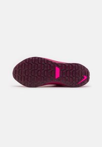 Semelle de chaussure de sport Nike en rose foncé, présentant un motif en caoutchouc texturé, un logo en contour rose vif et une semelle intermédiaire renforcée.