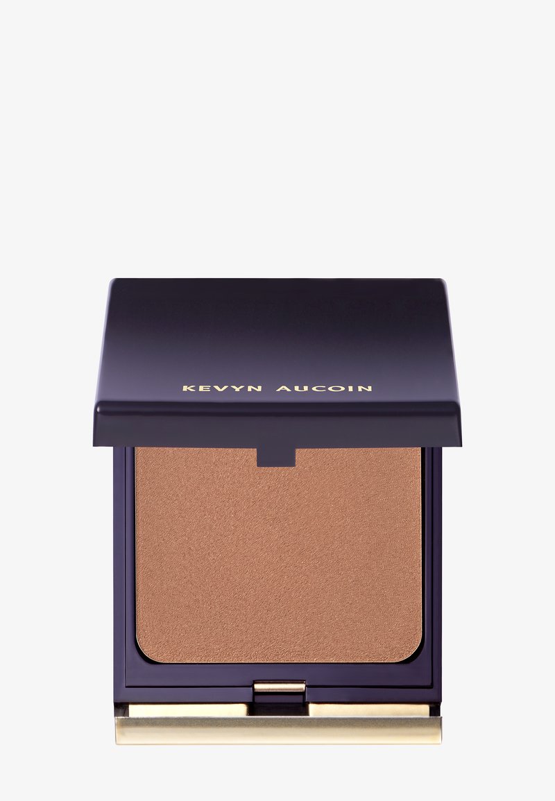 Pressed bronzer in a dark purple compact with a metallic gold hinge. The bronzer has a smooth, matte finish in warm brown tones.
