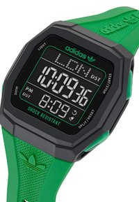 Montre de sport numérique avec un cadran noir, des accents verts et un bracelet en silicone vert. Résistante aux chocs et dotée d'un bracelet texturé.