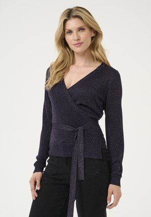 V-neck wrap sweater in dark purple with metallic threads, long sleeves, and a tie belt detail at the waist, paired with black pants.