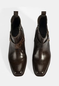 Bottines en cuir marron avec un motif crocodile, fermetures éclair latérales et accent de matériel décoratif au niveau de la cheville. Fini lisse et brillant.