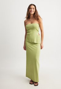 Grön, ribbad, strapless maxiklänning med sidofrackar; slät textur och åtsittande silhuett; matchad med platta sandaler.