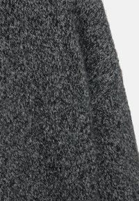 Szürke kötött anyag, amely texturált mintázatot mutat változó szürke árnyalatokkal, puha megjelenéssel és otthonos külsővel. Nincsenek jellegzetes fémalkatrészek vagy díszítések.