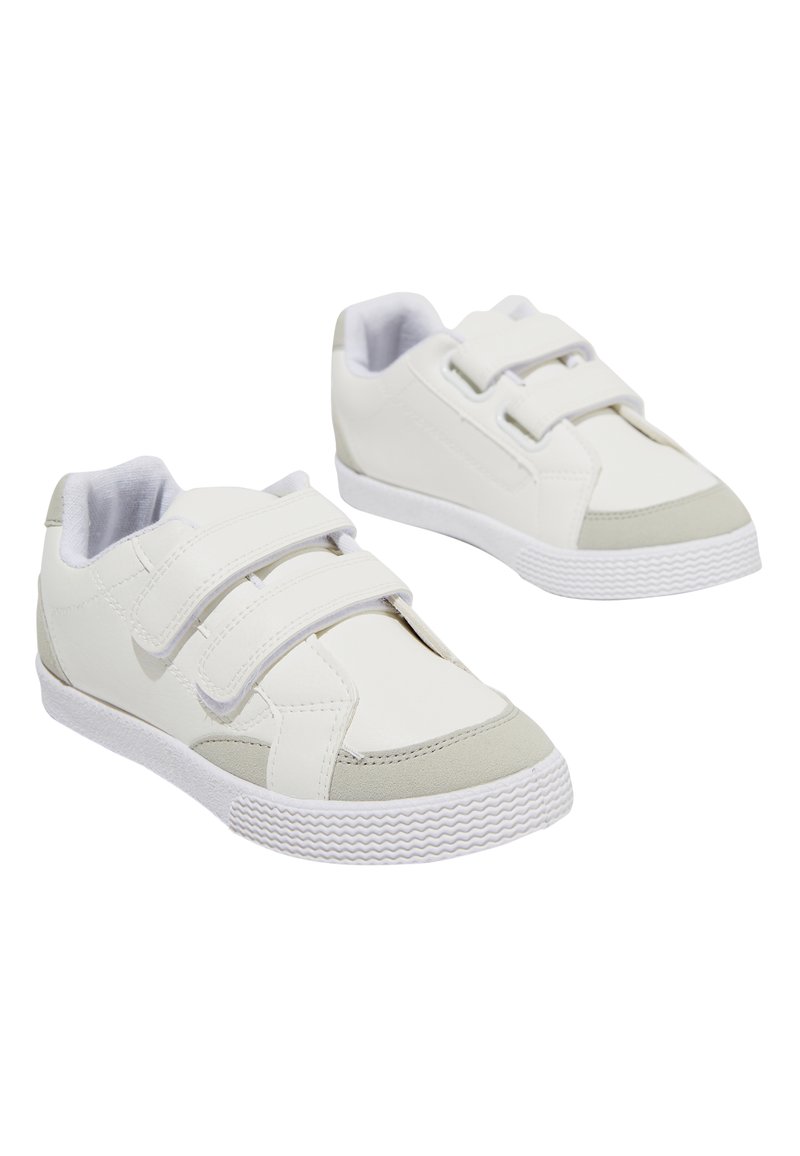 Une paire de baskets blanches pour enfants avec deux bandes auto-agrippantes et des détails gris clair sur la pointe et le talon, sur fond blanc.