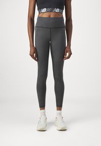 Szürke, magas derekú leggings sima textúrával, kontrasztos varrással. Fekete, cropped toppal és fehér tornacipővel viselve.