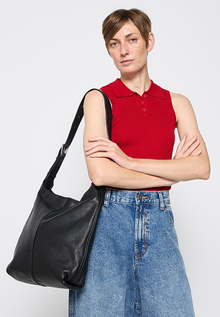 Schwarze Leder-Schultertasche mit glatter Oberfläche und geschwungenem Design. Sie besitzt einen langen Tragegurt und minimalistische Nähte.