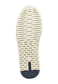 Suela de zapato de goma blanca con patrones de agarre texturizados. Presenta numerosas perforaciones y un acento de color azul marino en el talón. Logo de la marca visible.