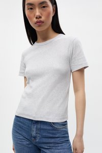 T-shirt grigio a manica corta, con collo a giro, in un tessuto morbido e texturizzato. Abbinato a jeans di denim blu, evidenziando semplicità e comfort.