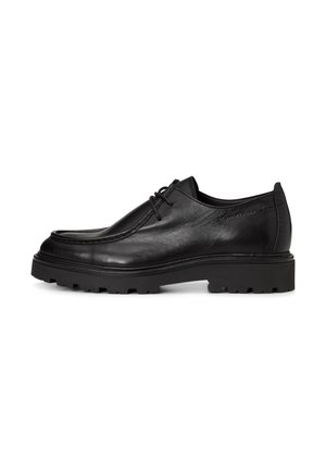 Chaussure en cuir noir à lacets avec semelle épaisse à crampons et détails cousus, vue de profil sur fond blanc.
