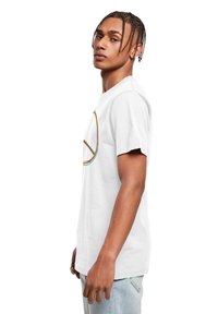 Hvid t-shirt med et farverigt fredssymbol grafik, korte ærmer, rund hals og en afslappet pasform, parret med lyseblå denim jeans.
