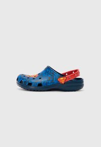 Blue and black clogs with a textured design, featuring Superman logos on the sides and a red strap at the back for secure fit.