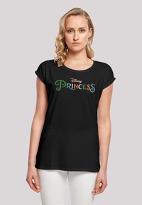Svart T-skjorte med rullede ermer, prydet med "Disney Princess"-logo i fargerik, leken typografi. Myk stoffkvalitet, avslappet passform.