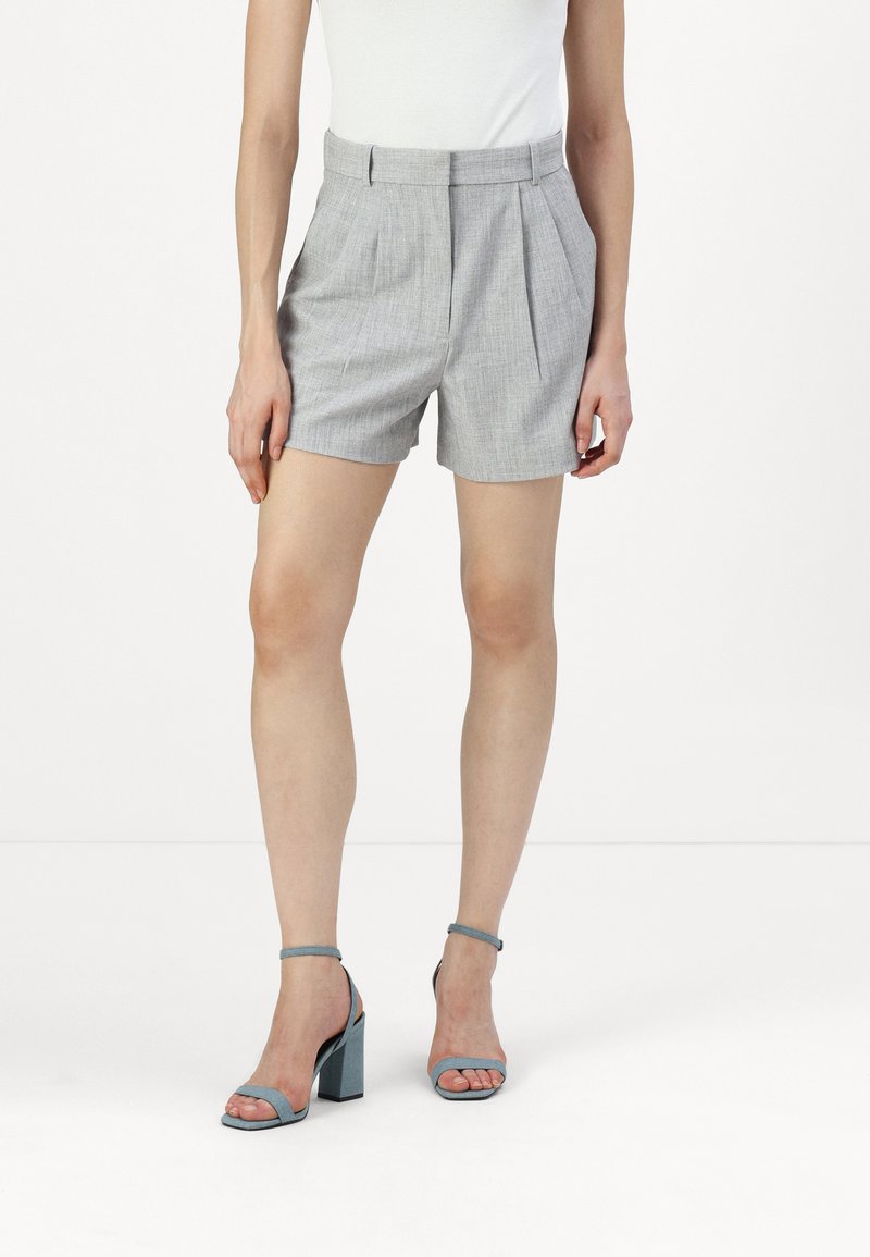 Gray pleated shorts made of lightweight fabric, featuring a high waist and a classic fit. Paired with blue block-heeled sandals.