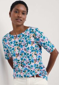 Short-sleeve top in vibrant floral print featuring blue, green, and purple hues on a light pink background, with a round neckline and relaxed fit.