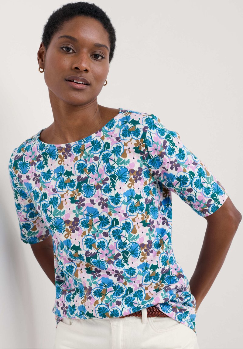 Short-sleeve top in vibrant floral print featuring blue, green, and purple hues on a light pink background, with a round neckline and relaxed fit.