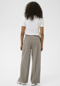 Pantalons larges taille haute gris clair avec des rayures blanches verticales, dotés de deux poches arrière et d'un tissu à texture lisse.