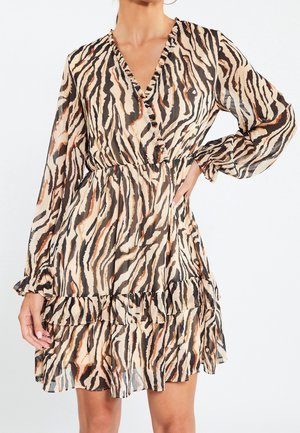 Robe imprimée animal en beige avec des rayures noires et rouillées, présentant un décolleté en V profond, des manches longues et un ourlet froncé. Fabriquée en tissu léger.