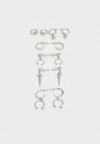 Ensemble de boucles d'oreilles en argent présentant divers designs : créoles, puces et styles pendants, avec des accents de billes et des éléments pointus.