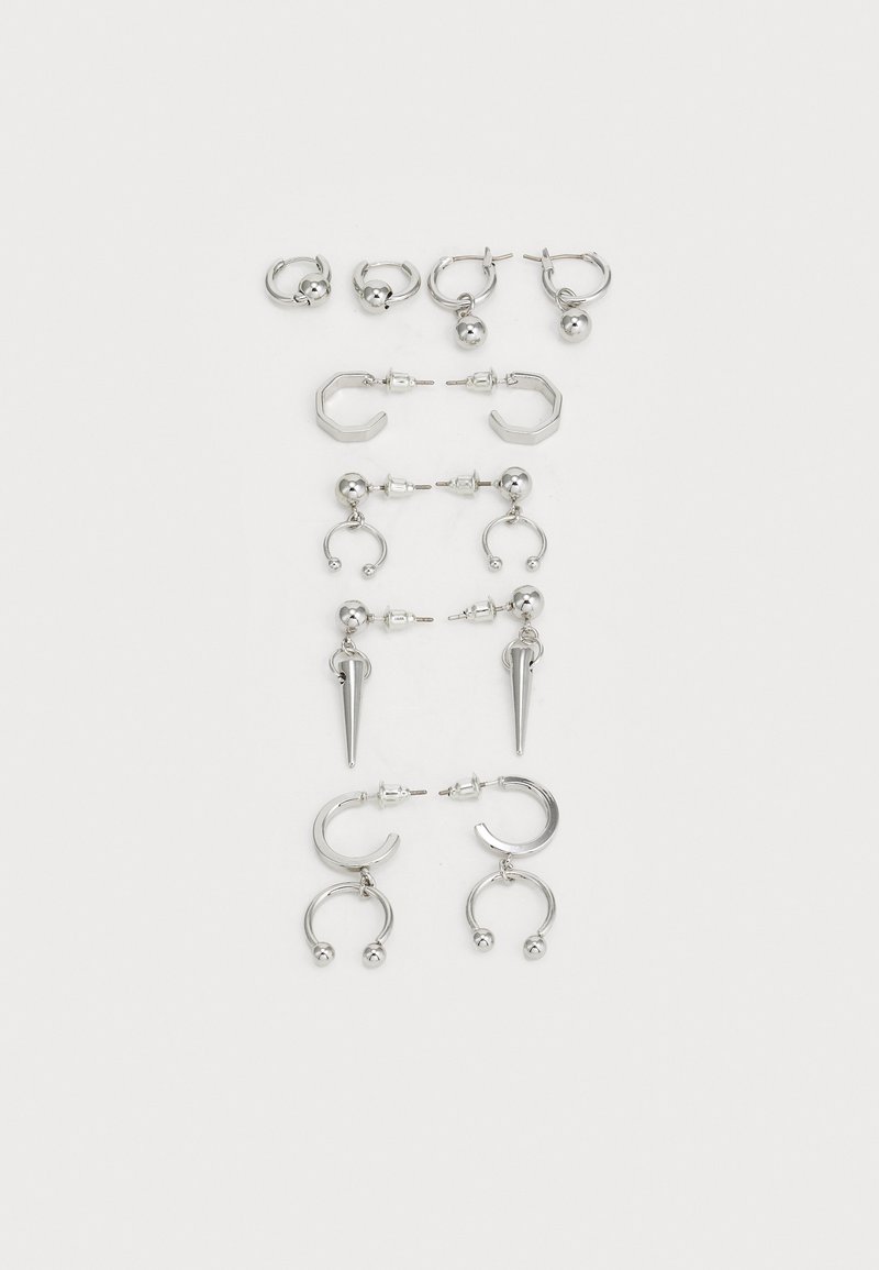 Ensemble de boucles d'oreilles en argent présentant divers designs : créoles, puces et styles pendants, avec des accents de billes et des éléments pointus.