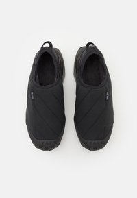 Black slip-on shoes with quilted fabric upper, rubber sole, and textured grip. Features a pull tab at the heel for easy wear.