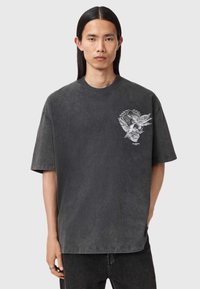 Tumši pelēks pārmērīgi liels T-krekls, izgatavots no mīkstas kokvilnas, ar novecojušu apdari un detalizētu grafiku ar galvaskausu ar spārniem uz krūtīm.