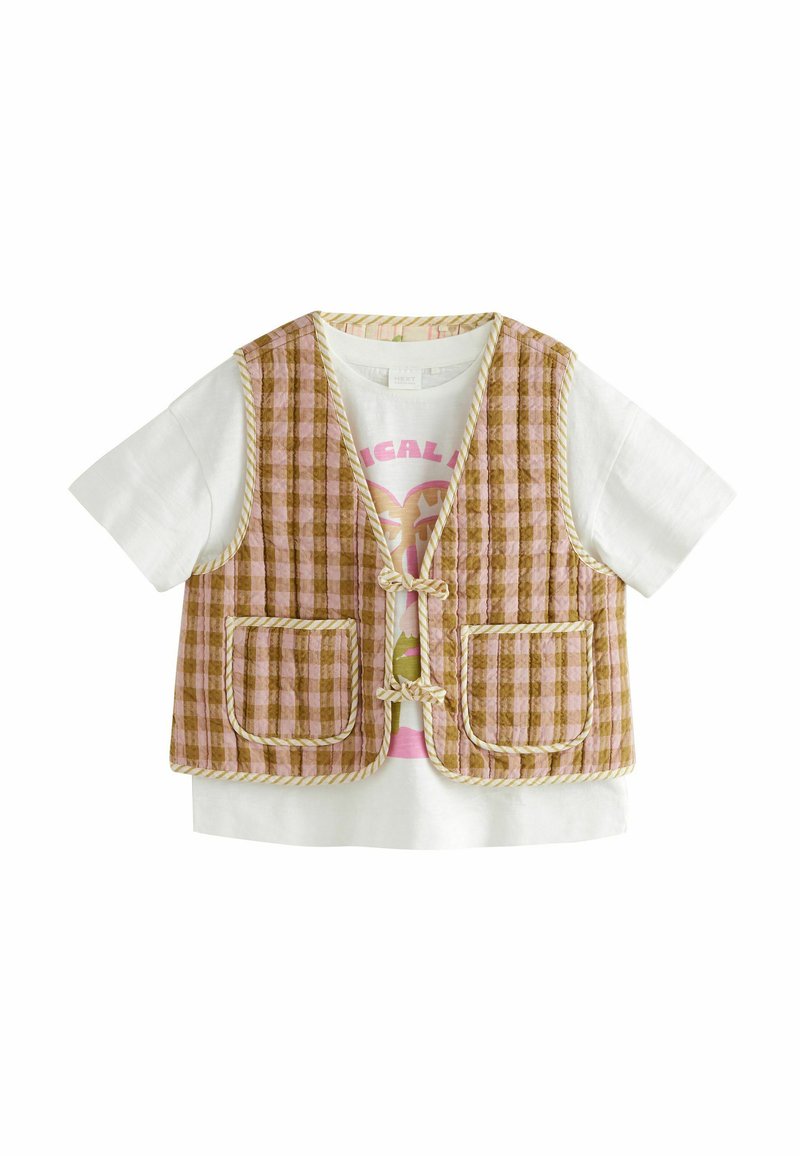 Gilet à carreaux rose et marron avec deux poches avant et des bords jaunes, porté par-dessus un t-shirt blanc avec un design graphique rose.