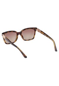 Gafas de sol de carey con forma de ojo de gato, lentes degradados y ornamentación dorada en las patillas. Textura suave; diseño moderno.