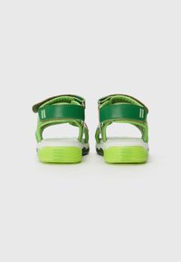 Sandales vertes avec deux sangles réglables, semelles rembourrées et semelle texturée. Présente une semelle extérieure contrastante blanche et vert citron.