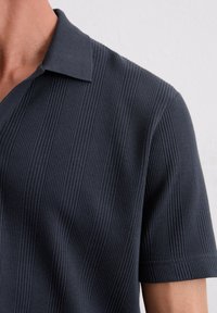 Dunkelblaues Polohemd mit kurzen Ärmeln aus strukturiertem, geripptem Material. Verfügt über einen klassischen Kragen und einen ordentlich verarbeiteten Saum.