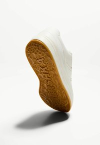 Fehér bőr sportcipő vastag talppal; a texturált gumitalp méhsejt mintázattal és domború logóval rendelkezik.