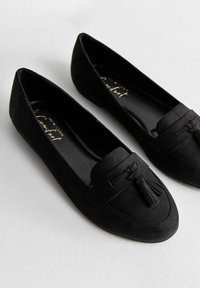 Zwarte platte schoenen van zacht suede. Heeft een ronde neus en een decoratieve franjes aan de voorkant. Glad zwart binnenwerk.