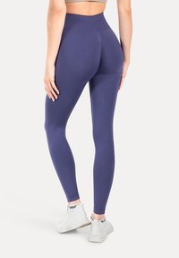 Wysokie legginsy w kolorze granatowym, wykonane z elastycznego materiału, charakteryzujące się gładką fakturą i subtelnym przeszyciem z tyłu.
