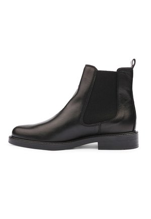 Bottine Chelsea en cuir noir avec panneau latéral élastique, languette au talon et petit talon empilé sur fond blanc.
