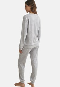 Grijs gestreept pyjama set bestaande uit een lange mouwen top en bijpassende broek. Zacht materiaal met gestructureerde verticale lijnen en geribbelde manchetten.