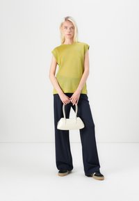 Lime green short-sleeve top with textured fabric, worn with navy wide-leg trousers and a small white handbag. Footwear is black and beige.
