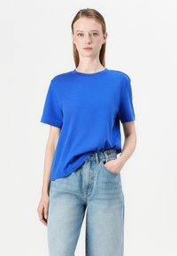 Blå kortärmad t-shirt i mjukt tyg, med rund halsringning och avslappnad passform, i kombination med ljusblå denimjeans.